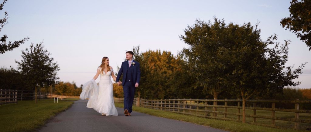 A still from wedding video with Bride and groom walking at the Mythe Barn
